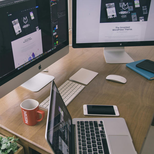An iPhone and iMac and 2 large screens on a desk