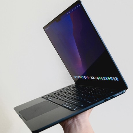Black coloured Mac held open in the air